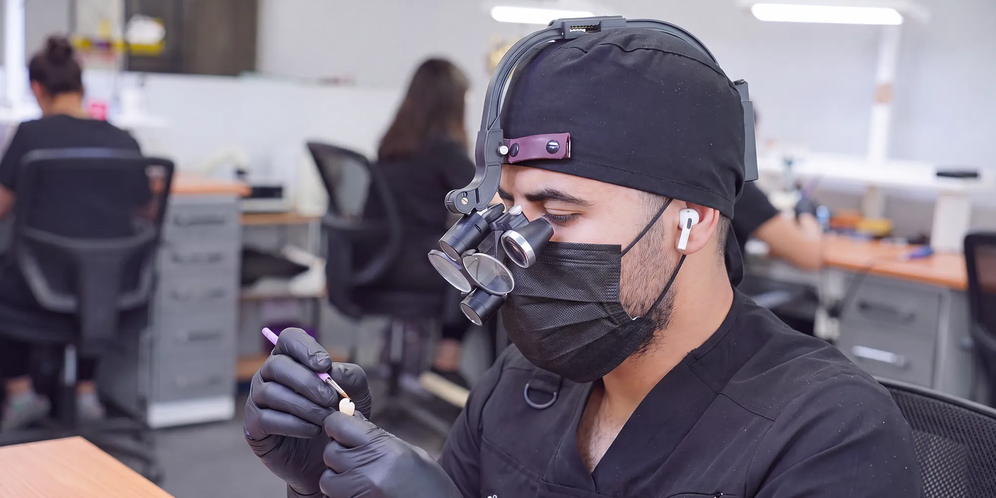 Un técnico de DentakayLabs con lupas de aumento termina una restauración
